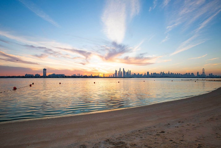 Fairmont The Palm Beach shoreline with city skyline at sunset