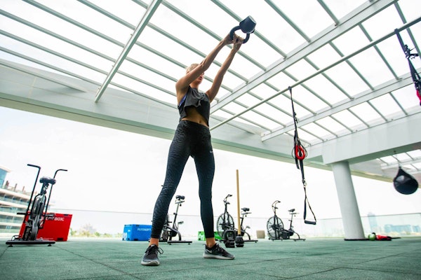 Woman exercising with a kettlebell in a modern gym.