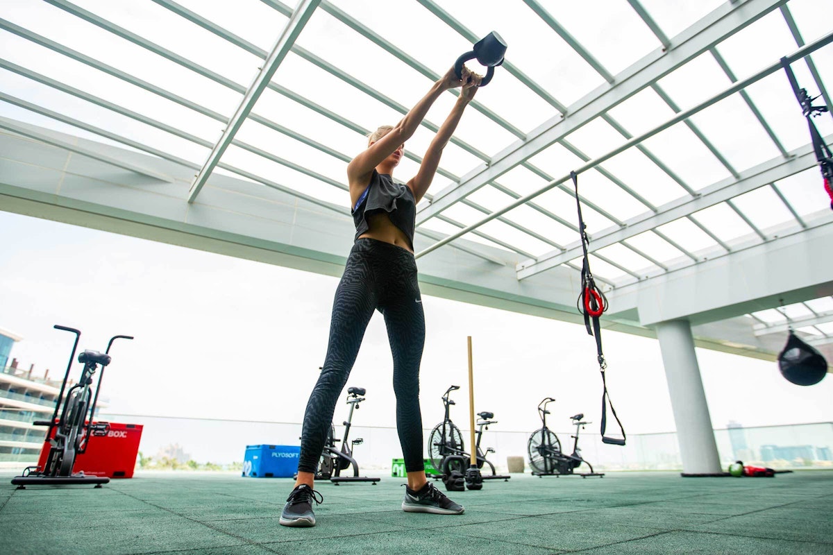 Woman exercising with a kettlebell in a modern gym.