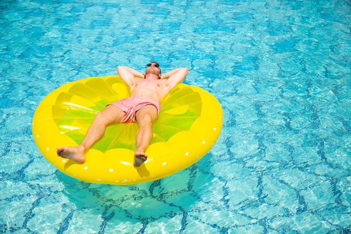 Man relaxing on a yellow pool float in clear water