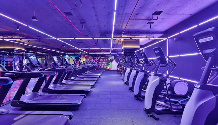 StudioRepublik A modern gym interior featuring several treadmills lined up under vibrant purple and pink neon lights.