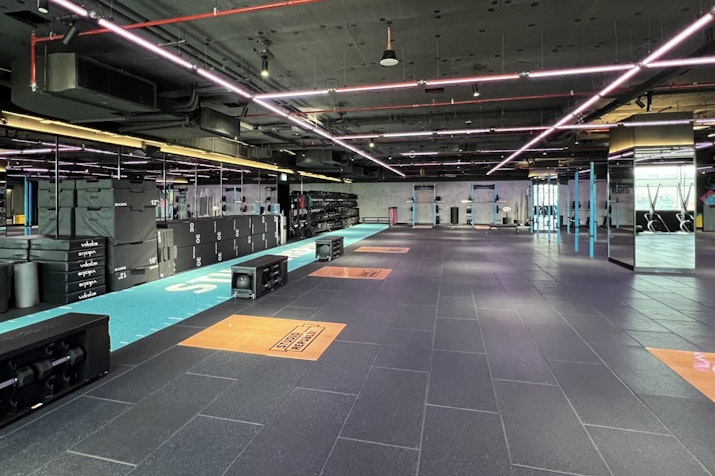 A spacious gym area featuring workout equipment and colorful lighting.
