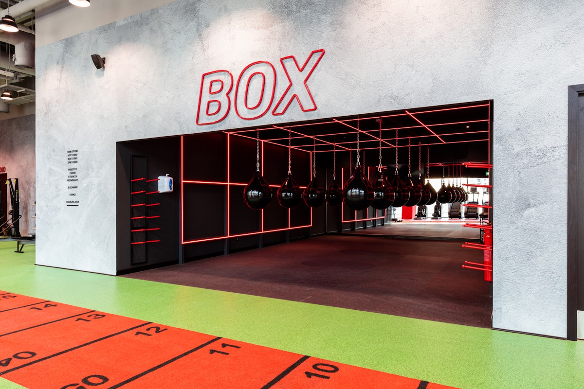 Boxing area with red and black interior design and hanging punching bags.