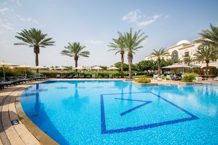 Outdoor swimming pool with palm trees and lounge chairs