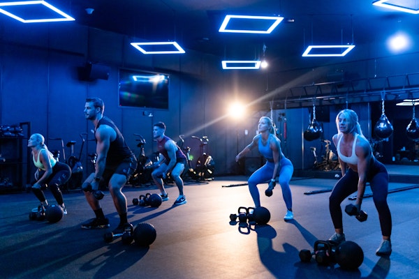 Vital Role of Company Fitness Benefits in Employee Perks: group workout session in a modern gym.