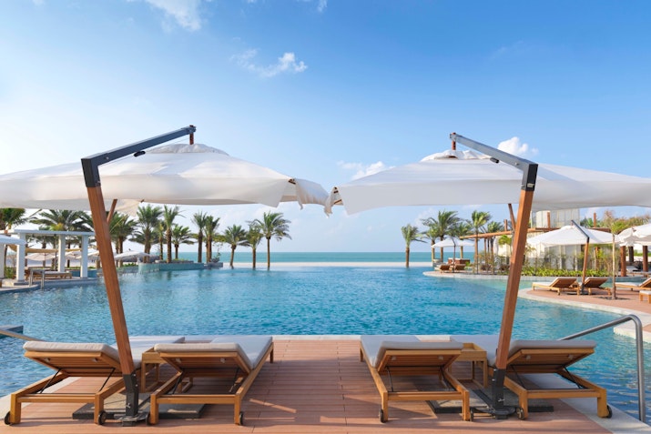 Lounge chairs and umbrellas by a luxurious pool with ocean view