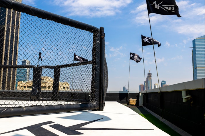 Outdoor boxing ring and vibrant city surroundings.