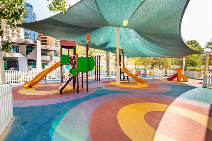 Colorful playground with slides and climbing structure under a shaded canopy