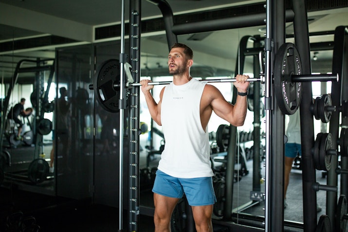 W Dubai The Palm Gym Man performing a barbell squat in the gym.