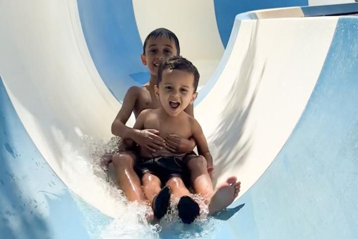 Two children enjoying a ride on a water slide.
