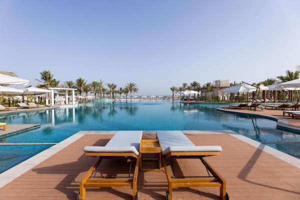 Poolside loungers with a clear view of the luxurious swimming pool and surrounding palm trees.
