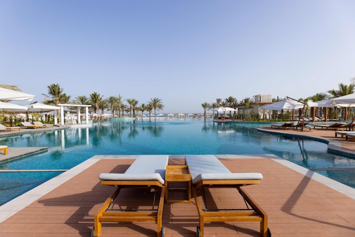 Poolside loungers with a clear view of the luxurious swimming pool and surrounding palm trees.