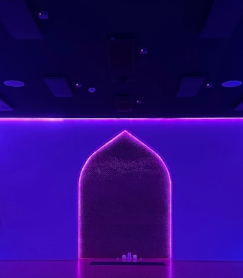 TruFusion Dubai A dimly lit room with purple and blue neon lights outlining an archway, creating a vibrant and modern atmosphere.
