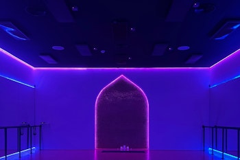 A dimly lit room with purple and blue neon lights outlining an archway, creating a vibrant and modern atmosphere.