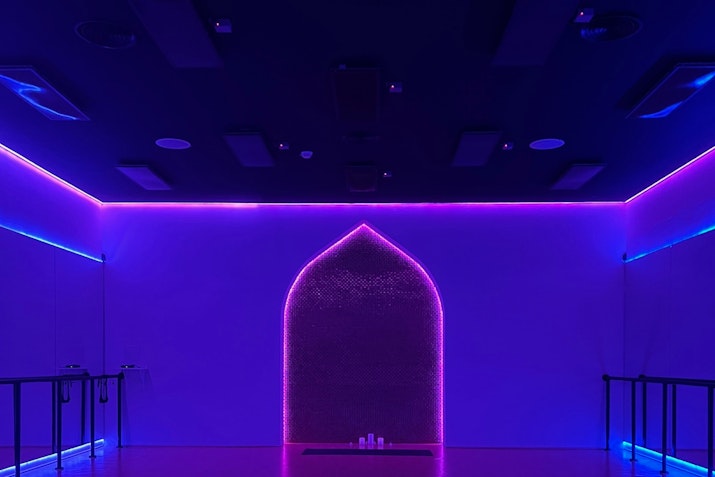 A dimly lit room with purple and blue neon lights outlining an archway, creating a vibrant and modern atmosphere.