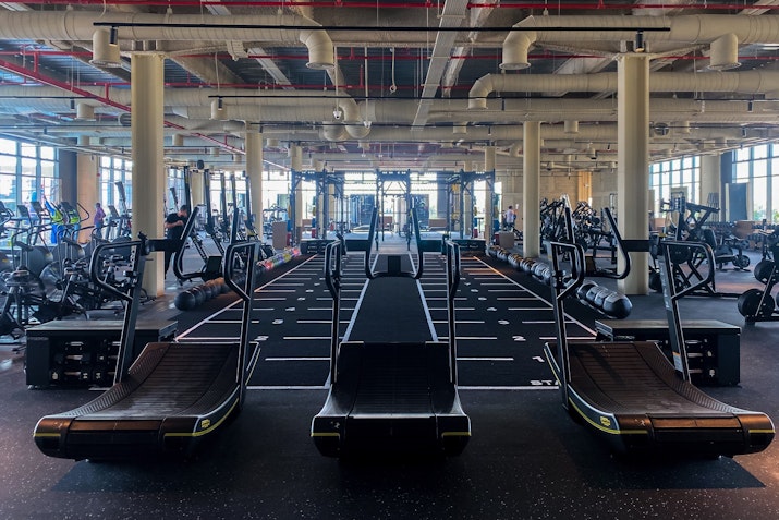 A spacious gym with rows of treadmills and exercise machines.