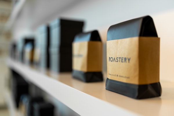 Several bags of coffee labeled "ROASTERY" lined up on a shelf.