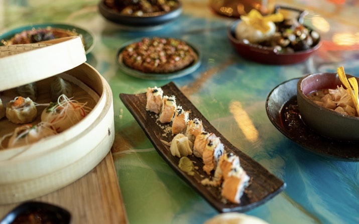 Assorted sushi and Asian dishes on a colorful table