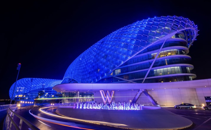 Modern hotel building illuminated with blue lights at night.