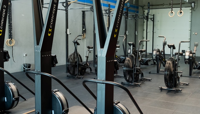 SK Fitness Gym setup featuring Concept2 rowing machines and bikes, along with various fitness equipment, in a modern, industrial-style gym with black tiled flooring