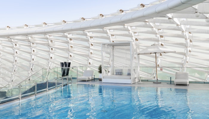 W Abu Dhabi - Yas Island Luxurious indoor pool area with a sleek, curved roof structure and stylish lounge seating, offering a tranquil ambiance.