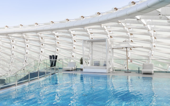 Luxurious indoor pool area with a sleek, curved roof structure and stylish lounge seating, offering a tranquil ambiance.