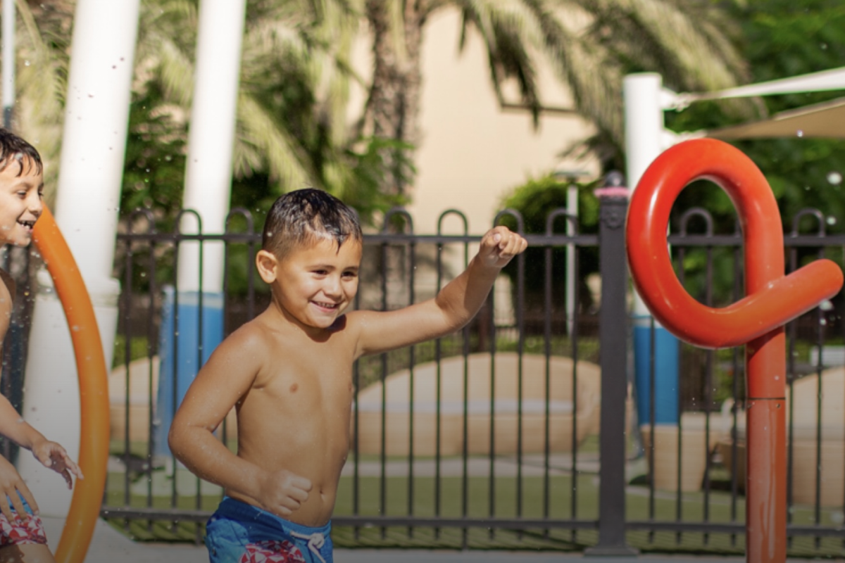 End School Break With a Splash Children enjoying a splash pad with colorful water features.