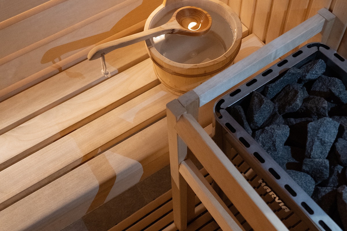 Close-up of a wooden sauna interior featuring a bucket with a ladle and heated stones, creating a classic sauna ambiance.