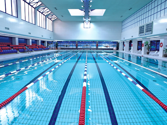 Indoor swimming pool with lane markers and seating.