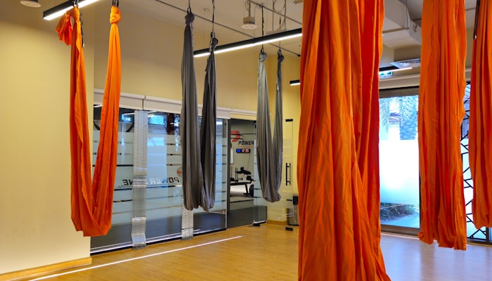 Elev8 Fitness studio with wooden floors and red and black swing yoga drapes hanging from the ceiling