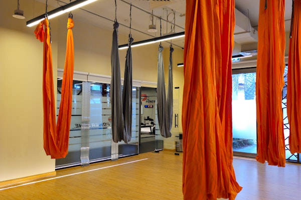 Fitness studio with wooden floors and red and black swing yoga drapes hanging from the ceiling