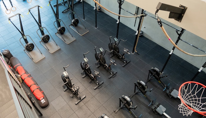 SK Fitness Aerial view of a gym with rowing machines, air bikes, ski ergs, and a wall rig with ropes, setup for cardio and strength workouts.