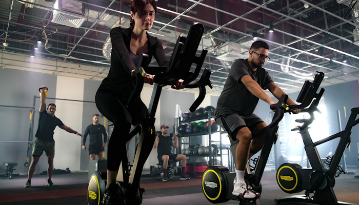 GRITNCODE Male and female in a fitness class, cycling