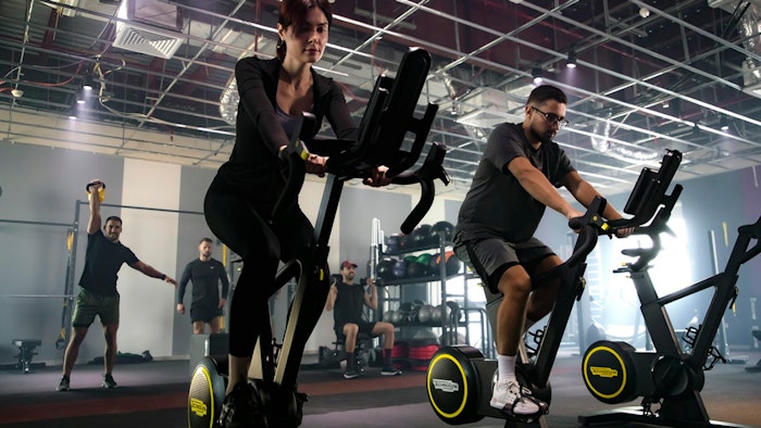 Male and female in a fitness class, cycling