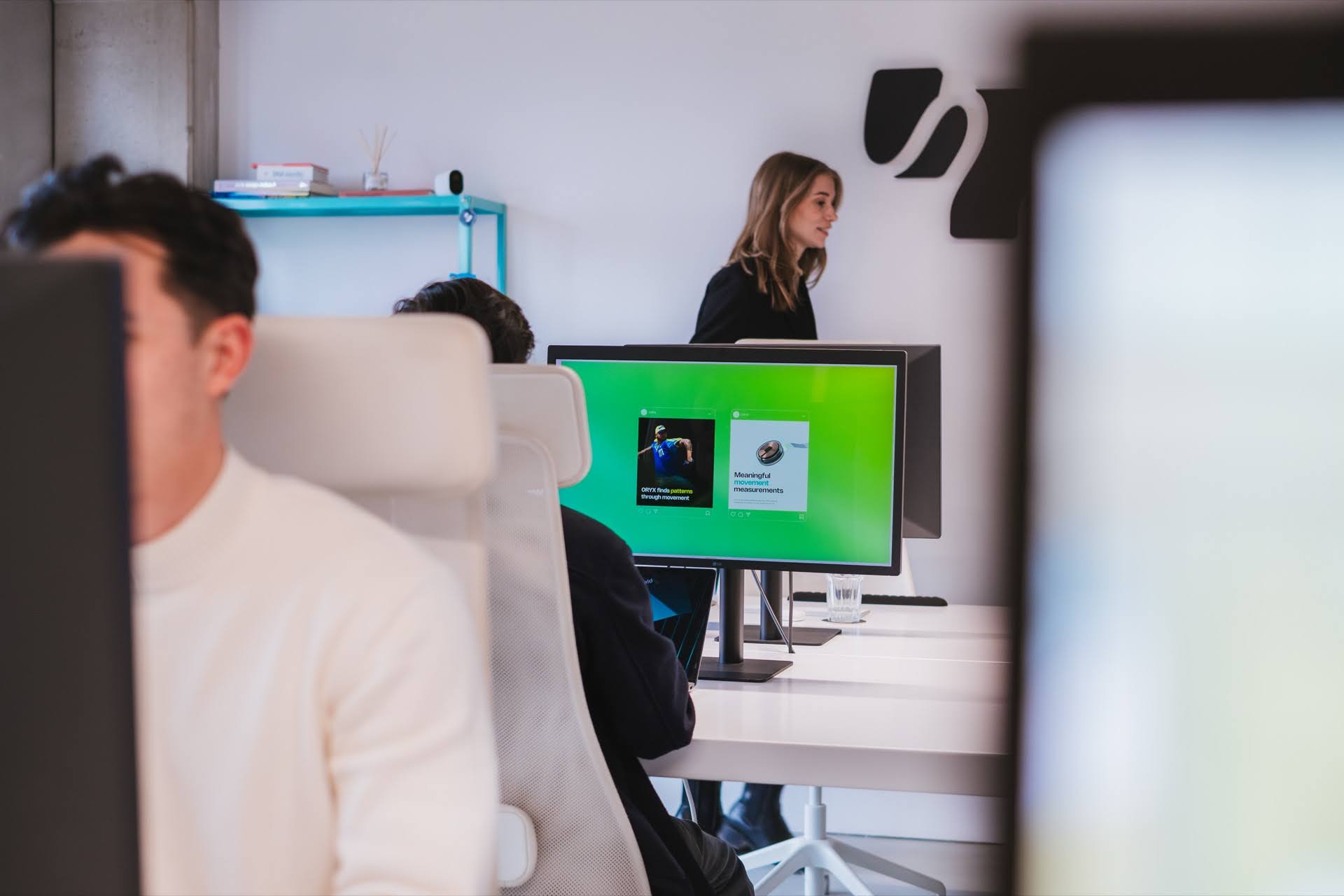 Light office with people behind monitors working focused on green graphics on a monitor