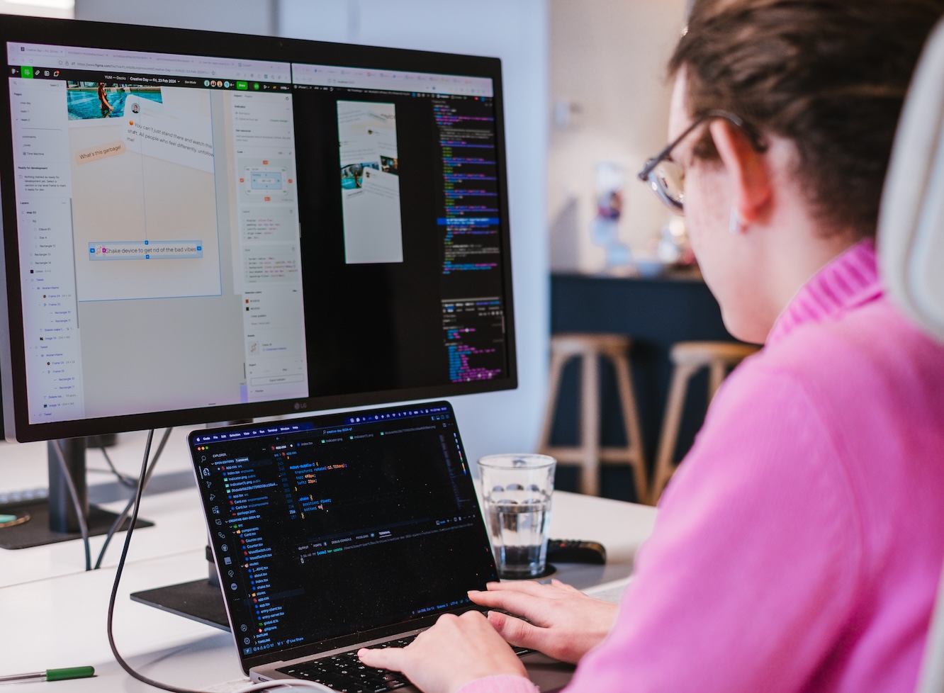 Person sitting in front of laptop and monitor that shows code