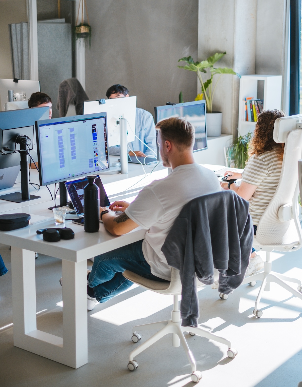 A group of people working around white desks