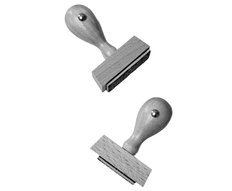 Two wooden rubber stamps with metal bolts on the handles, positioned diagonally and facing opposite directions on a plain, white background.