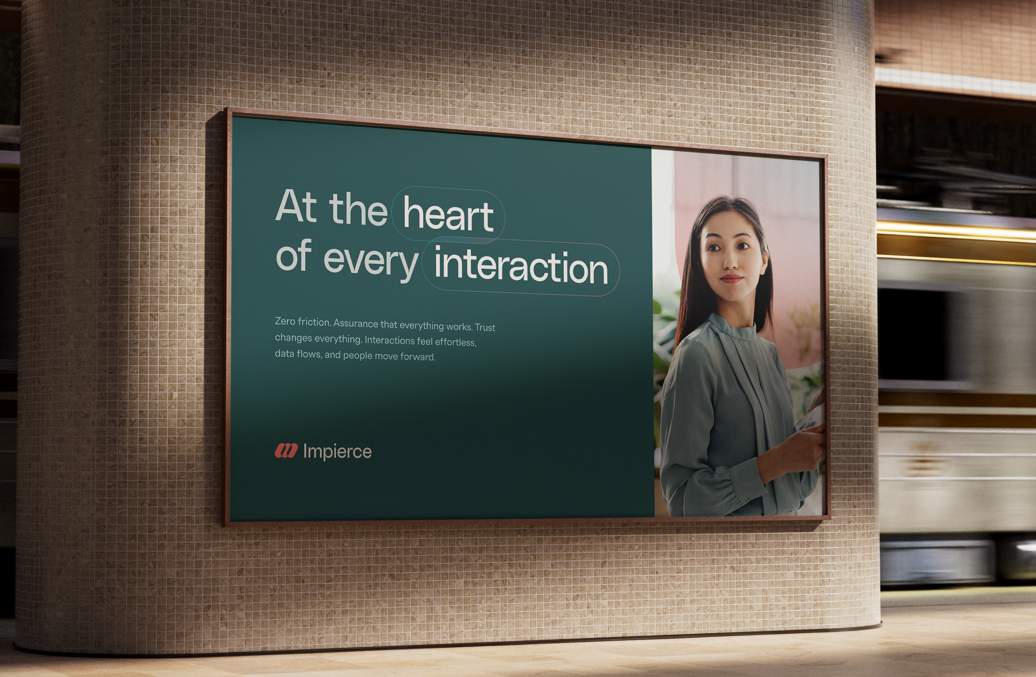 A subway station features a billboard with the text "At the heart of every interaction" beside a woman in a light blue blouse. The ad is for a company named Impierce, and a train is blurred in the background.