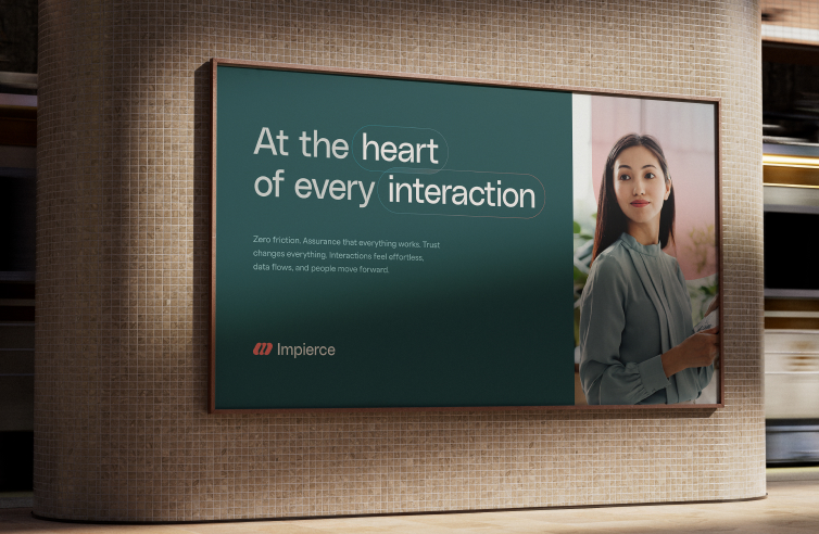 A subway station features a billboard with the text "At the heart of every interaction" beside a woman in a light blue blouse. The ad is for a company named Impierce, and a train is blurred in the background.