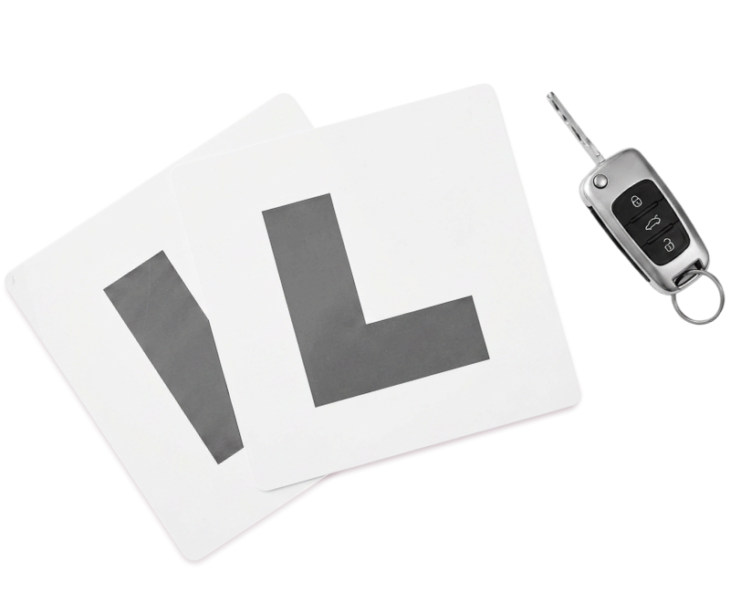 Two learner driver 'L' plates overlap next to a car key with a remote on a white background.