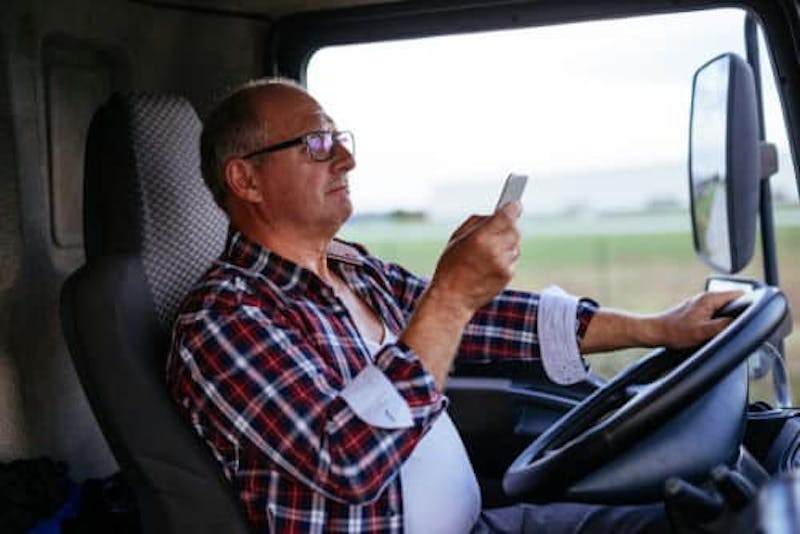 Older man in flanel shirt driving a truck