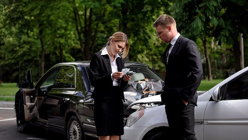 People looking at their cars after a car accident