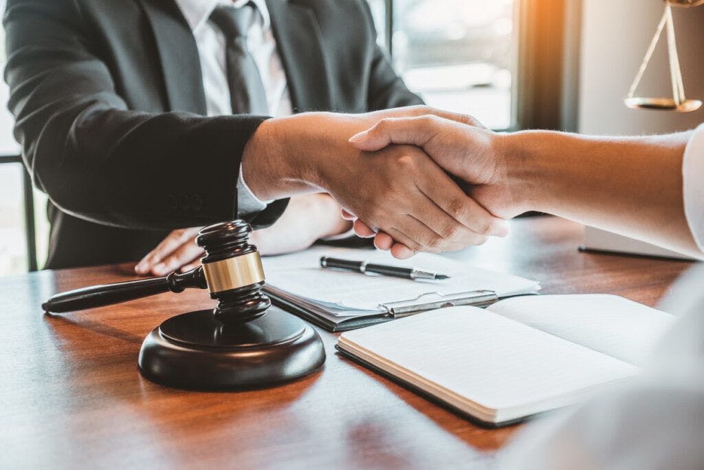Two people shaking hands across a desk