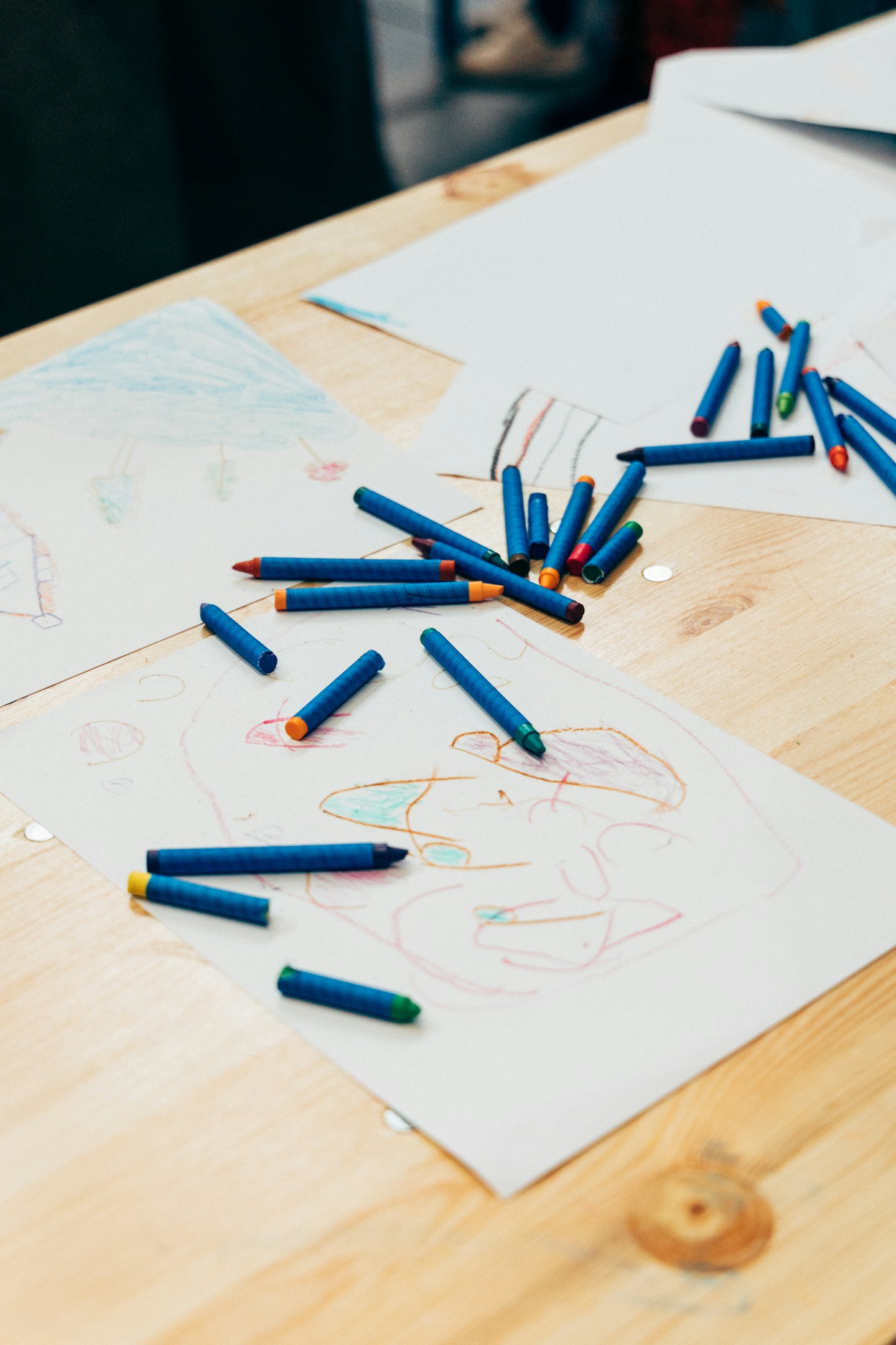 Colorful pencils and children drawings on table