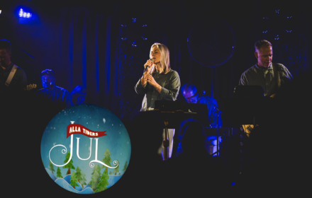 Alla Tiders feat. Karolina Nyström sjunger på scen i blått ljus