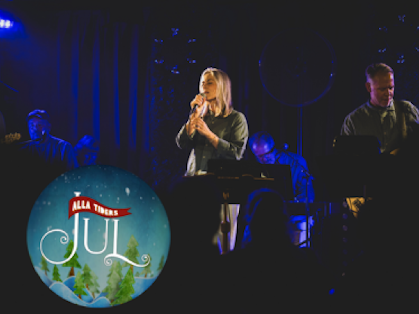 Alla Tiders feat. Karolina Nyström sjunger på scen i blått ljus