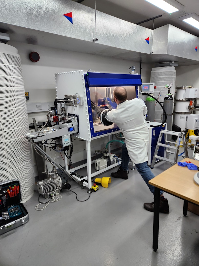 Scientist reaching into cryogenic glovebox system