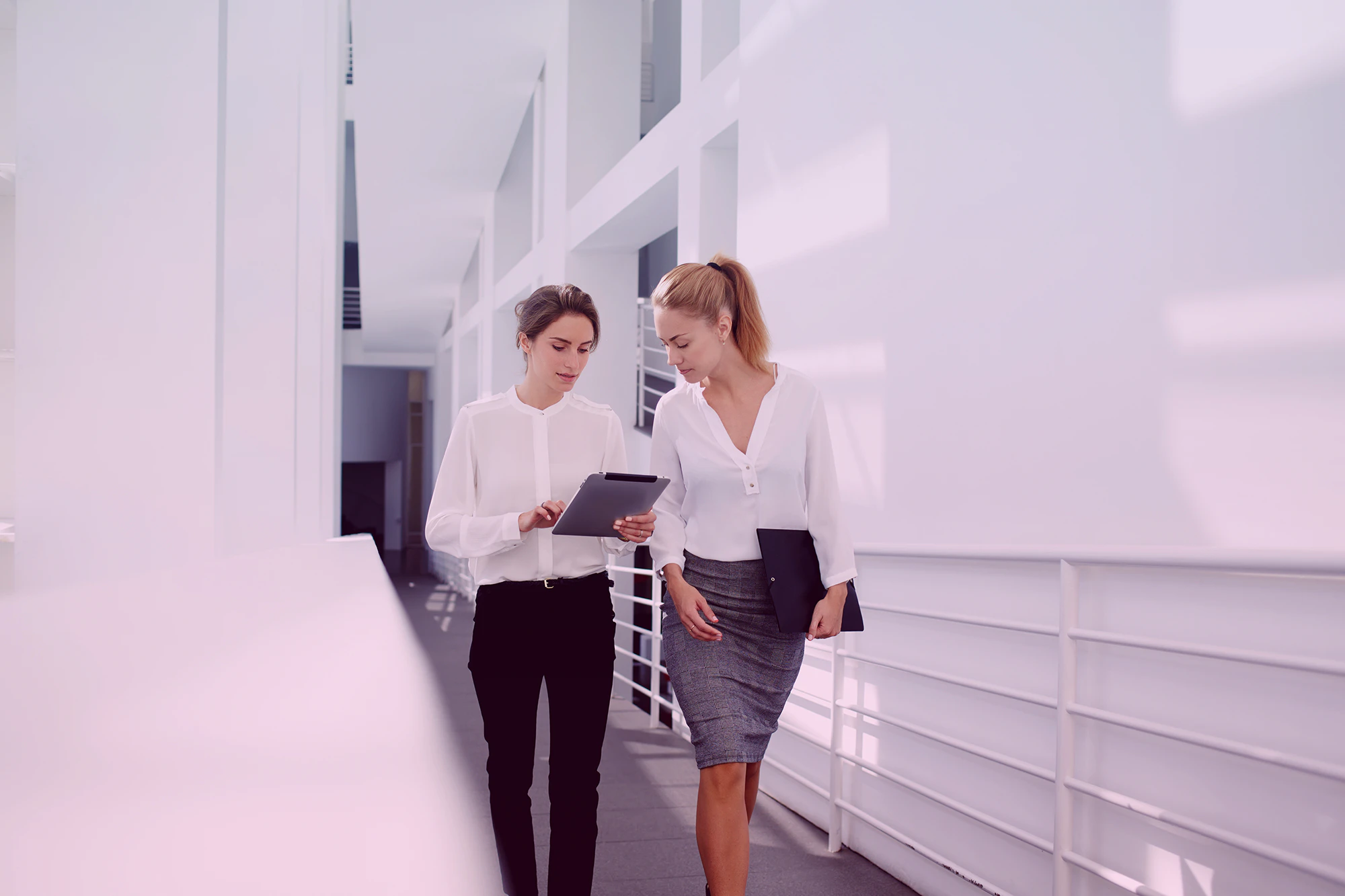 Women walking through hallway and holding an iPad