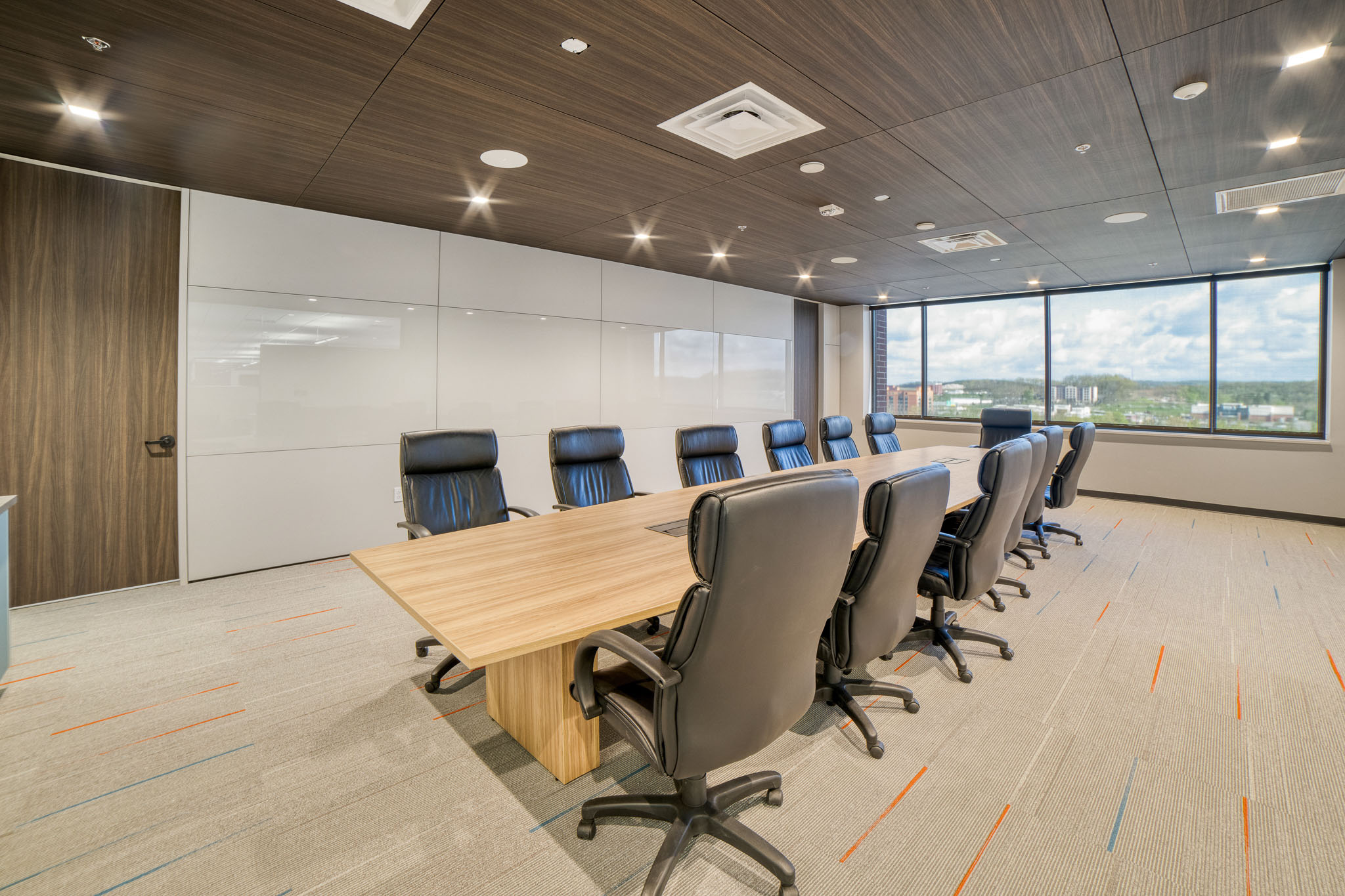 Interior view showcasing Falkbuilt's solid wall construction in a corporate setting with back-painted glass and acoustic paneled ceiling